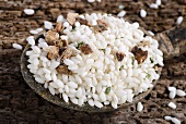 Vialone Nano risotto rice with dried porcini mushrooms, pink peppercorns and parsley on a wooden spoon