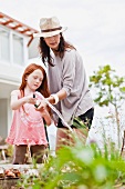 Mother and daughters watering plants in garden