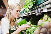 Verkäuferin prüft Salat in der Gemüseabteilung