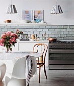 Dining area with various chairs in front of a modern kitchenette, above pendant lights