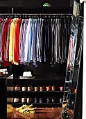 Shirts arranged by colour and shoes in black-painted, walk-in wardrobe