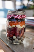 Assorted sweets (jelly beans, liquorice and chocolate drops) in a jar as a gift