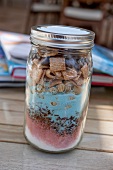 Different colours of sugar, cornflakes and chocolate drops layered in a jar as a gift