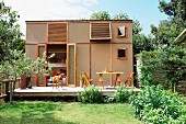Summer atmosphere in garden with terrace adjoining cubic prefab house