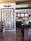 Kunstobjekte freistehend und an Wand in offenem Wohnraum mit rustikaler Holzbalkendecke