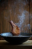 A pork chop being smoked in a wok