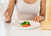 A young woman eating vegetables