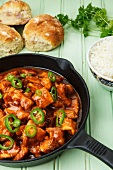 Spicy turkey goulash in a pan, with rice and bread rolls
