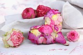 Decorative heart made from bound rose petals and rose blooms on monogrammed linen cloth