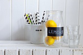 A jar of lemons, drinking straws and water glasses