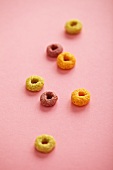 Pieces of breakfast cereal on a pink surface