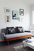 Fotogalerie über grauem Sofa im Retrostil, weisser Couchtisch mit verchromten Füssen auf Hochflorteppich
