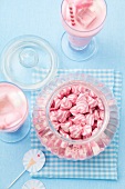 A jar of pink and white striped sweets, and a strawberry milkshake with marshmallows