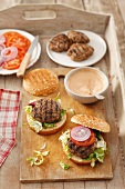 Home-made burgers with burger constituents on a wooden tray
