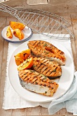 Grilled salmon steaks with orange wedges