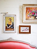 Gerahmte Bilder an Wand über teilweise sichtbarer Rückenlehne einer Sitzbank mit rotem Lederbezug und Rokoko-Holzgestell