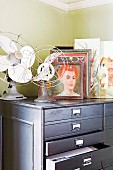 Vintage fans and collection of pictures on light grey chest of drawers