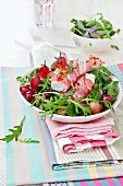 Chicken fillet wrapped in bacon on a bed of rocket with grapes