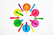 Colourful plastic plates, cups, bowls, spoons and forks