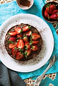 A small chocolate cake topped with fresh strawberries