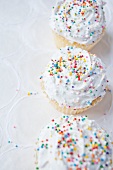 Cupcakes topped with whipped cream and colourful sugar pearls