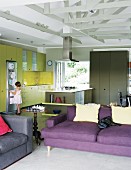 Offener, moderner Wohnraum mit kräftigen Farbakzenten in Wohn- und Kochbereich, Kind vor Kühlschrank