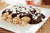 Chicken enchiladas with mole sauce, onion rings and goat's cheese