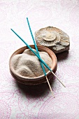 Fine sand in ceramic bowls, incense sticks and a fossil