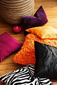 Colorful decorative pillows and a glass candle holder on parquet floor