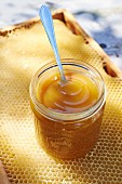 A jar of honey on top of a honeycomb