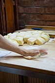 Hands shaping bread rolls in a bakery
