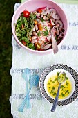 Summer Salad in a Pink Serving Bowl with a Bowl of Dressing