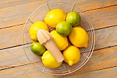 Lemons and limes in a wire basket with a lemon squeezer