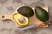 Fresh avocados on a chopping board with a knife