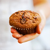 Hand holding a raisin muffin