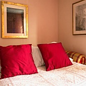 Doppelbett mit roten Kissen und Tagesdecke (Ausschnitt)