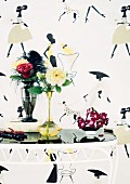 Various roses in vases on small table against fifties-style wallpaper