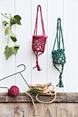 Lantern holders hand-crocheted from dyed jute yarn hanging on white wood panelling