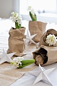 White hyacinths in crumpled bags of brown packing paper as festive table decoration