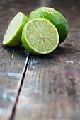 Two lime halves and a whole lime on a wooden surface