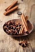 Star anise and cinnamon sticks in a dish on a wooden surface