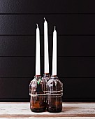 Candles in beer bottles covered in dripped wax with Christmas-tree tag