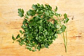 Fresh parsley, whole and chopped, on a wooden surface
