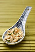 A spoon of noodle soup from China with chopped chives