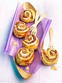 Nut-filled pastry whirls on purple paper in a wooden dish