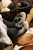 Hand-crocheted slippers on woman's feet next to basket of wool