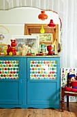 Blue-painted, half-height cabinet with printed paper behind glass door panels in child's bedroom