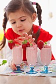 A girl with three strawberry milkshakes