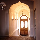 Elegantes Treppenhaus mit orientalischem Rundbogen und Blick auf Holz Eingangstür