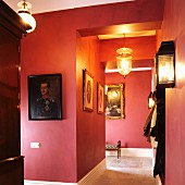 Red-painted hallway with gallery of ancestral portraits